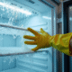 Personne en gants en caoutchouc retire la glace du congélateur